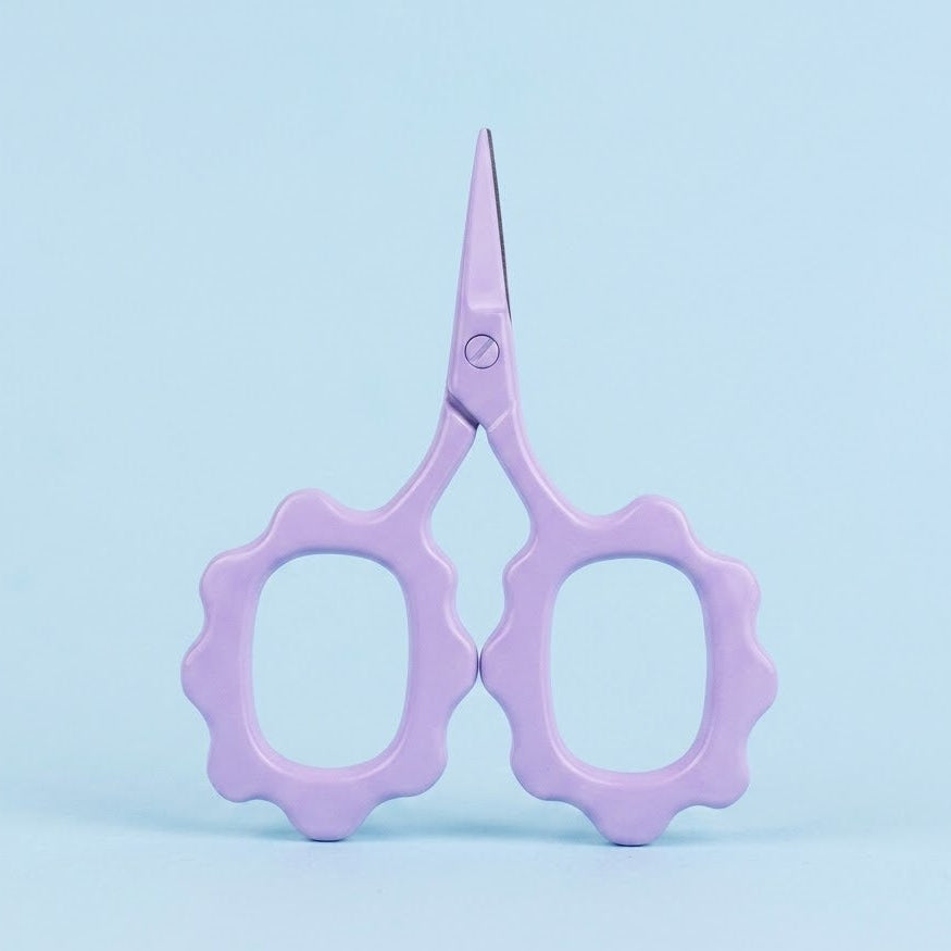 Purple scissors on a light blue background