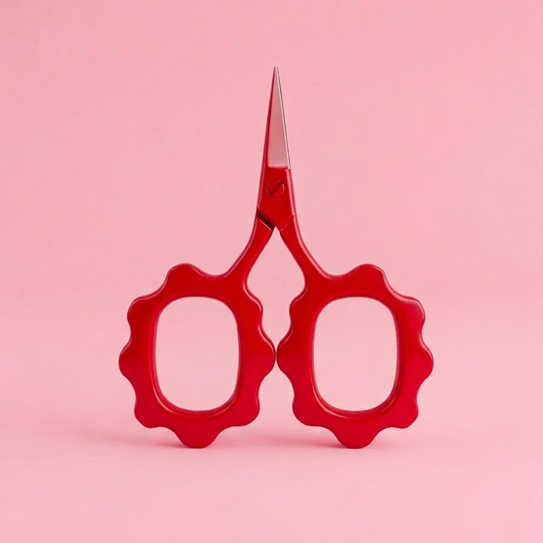 Red scissors with wavy handles on a pink background